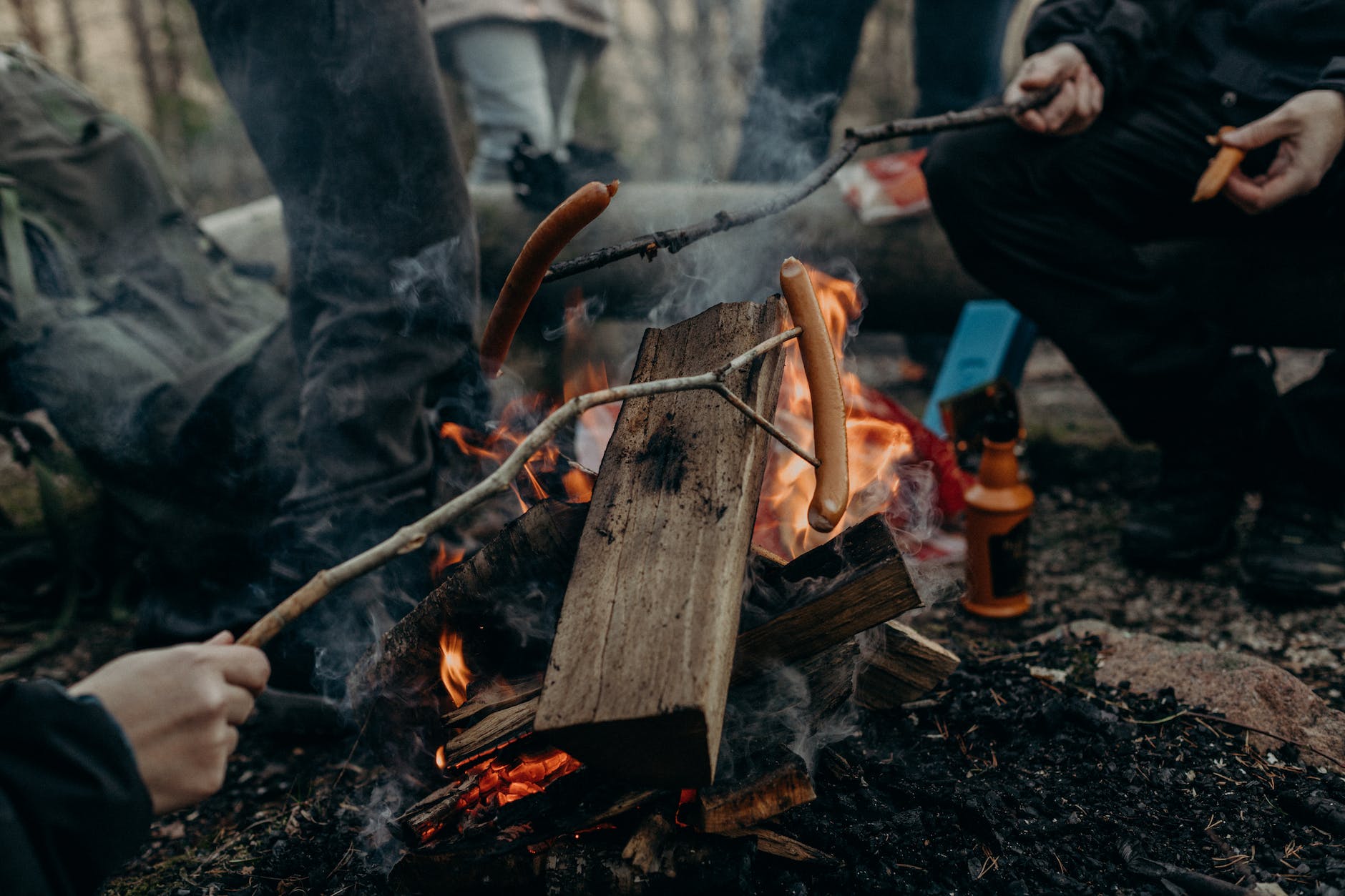 selective focus photography of people holding sticks with sausages